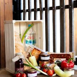Breakfast box with fresh vegetables, bread rolls, cheese and smoked meats in a wooden crate