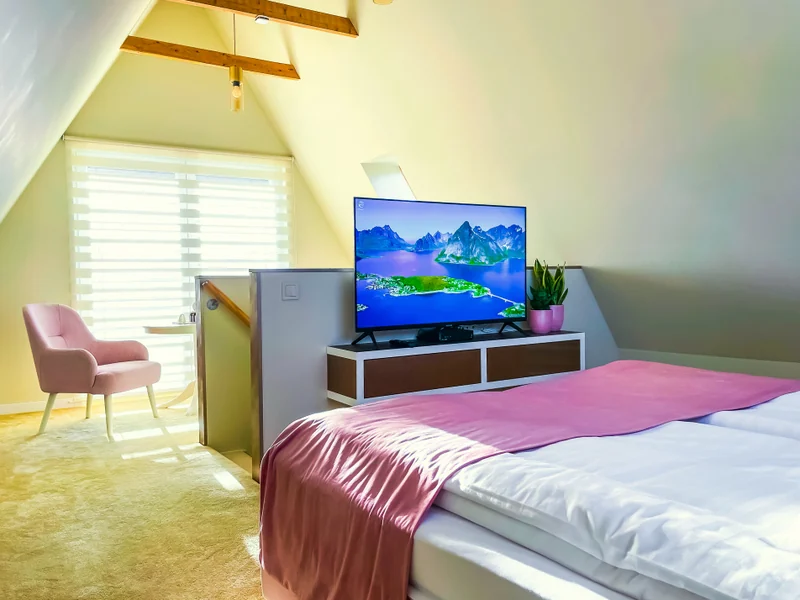 Bedroom with a pink armchair and TV