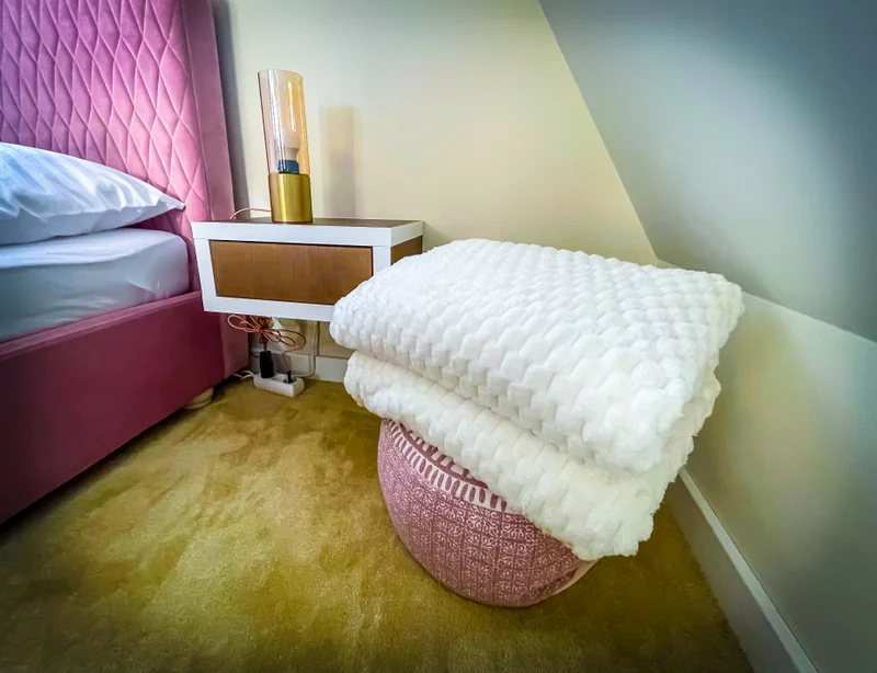 Soft blankets and a bedside lamp next to the bed